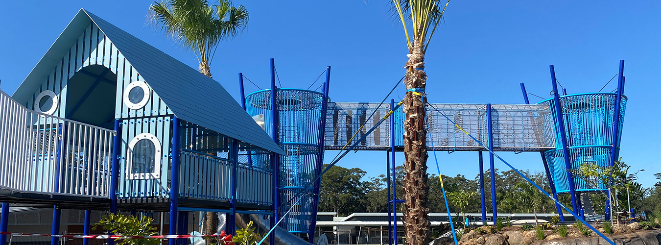 Outdoor playground equipment with climbing-net towers, rope bridges, and durable play structures
